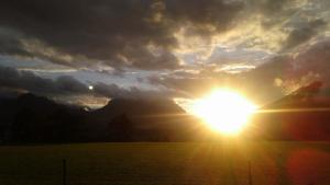 um pôr-do-sol num campo com o sol no céu em Haus Bichler em Kössen