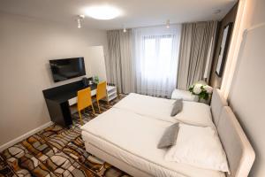 a hotel room with a white bed and a desk at Hotel Kazimierz in Kraków