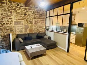 Una sala de estar con un sofá y una pared de piedra. en GITE URBAIN - Côté charme, en Rodez