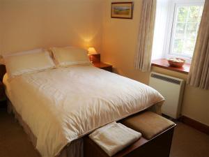 a bedroom with a white bed with a window at Branta Cottage in Dumfries