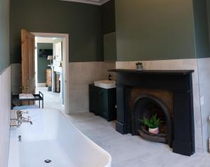 a bathroom with a bath tub and a fireplace at Riversdale House Bed & Breakfast in Llangollen