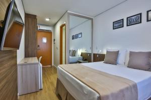 um quarto de hotel com uma cama grande e um espelho em Nobile Residences London Anapolis em Anápolis