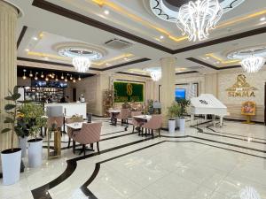 a lobby of a hotel with tables and a piano at Simma Hotel Spa & Waterpark in Tashkent