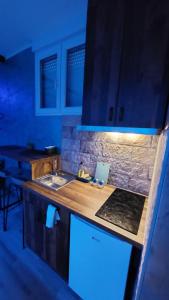 uma cozinha com um lavatório e um balcão com luzes azuis em Wonderland spa apartment em Niš