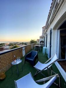 een balkon met stoelen en tafels en een tafel met wijnglazen bij Villa Farniente in Sète