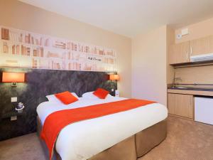 ein Schlafzimmer mit einem großen Bett mit roten Kissen in der Unterkunft Kyriad Angers Ouest Beaucouzé in Beaucouzé