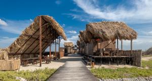 un ristorante con tetto di paglia e tavoli e sedie di CasaSolea a Mayapo