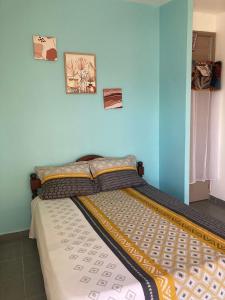 - un lit dans une chambre bleue avec 2 photos sur le mur dans l'établissement Central Appart, à Mamoudzou