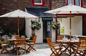two tables and chairs with umbrellas on a patio at Coorie Inn Restaurant and Rooms in Crieff