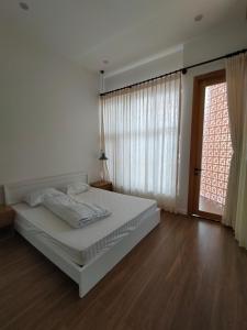a white bedroom with a bed and a window at Village Mai in Ấp Bình Hưng