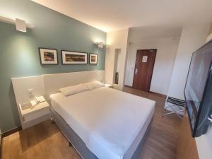 a bedroom with a white bed and a flat screen tv at Comfort Suites By Rei dos Flats in Brasília