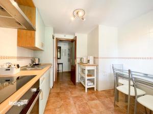 a kitchen with white cabinets and a table and chairs at HAA001) Apartamento moderno con jardín. in Ayamonte