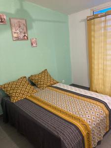 a bedroom with a bed with yellow and brown pillows at Central Appart in Mamoudzou