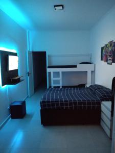 Schlafzimmer mit einem Bett, einem Schreibtisch und einem TV in der Unterkunft Apartamento Top Vista mar Boqueirao Gonzaga in Santos