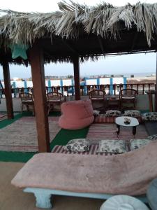 une terrasse avec un parasol, des tables et des chaises dans l'établissement Gina Motel Dahab, à Dahab