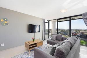 a living room with a couch and a tv at Modern 3 Bed Apartment Blouberg in Cape Town