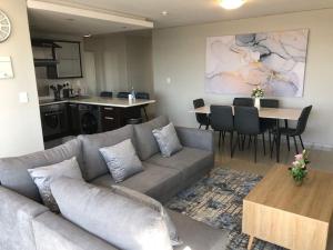 a living room with a couch and a table and a kitchen at Modern 3 Bed Apartment Blouberg in Cape Town