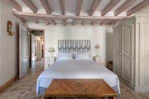 a bedroom with a white bed and a wooden table at La Chaumière in Ousson-sur-Loire