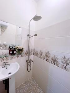 La salle de bains blanche est pourvue d'un lavabo et d'une douche. dans l'établissement Amy 2 Hostel Hue, à Hue