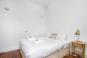 Dormitorio blanco con cama y mesa en 4 BR Edwardian family house wgarden, Notting Hill, en Londres