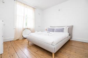 a white bedroom with a large bed and wooden floors at 4 BR Edwardian family house wgarden, Notting Hill in London