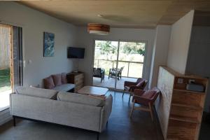a living room with a couch and chairs and a television at Maison bois Les Conches 6/8 Pers in Longeville-sur-Mer