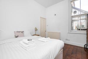 Un dormitorio con una cama blanca con toallas. en 4 BR Edwardian family house wgarden, Notting Hill, en Londres