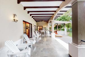a porch with white chairs and tables and a ceiling at Villa Coral in Playa Conchal