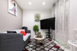 ein Wohnzimmer mit einem Sofa und einem Flachbild-TV in der Unterkunft Chic 2 pièces, épuré & pragmatic à 5' de Paris in Ivry-sur-Seine