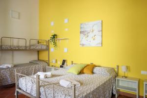 um quarto com 2 camas e uma parede amarela em B&B Pompei Hostel Deluxe em Pompeia