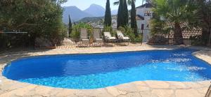a blue swimming pool with two chairs and a house at Casas de Almajar in Prado del Rey