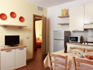 uma cozinha com uma mesa com uma televisão e uma cozinha com armários brancos em A semi detached bungalow with AC near the coast of Tuscany em La Caduta