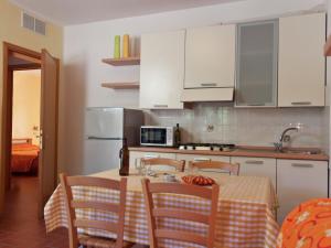 uma cozinha com uma mesa com cadeiras e um micro-ondas em A semi detached bungalow with AC near the coast of Tuscany em La Caduta
