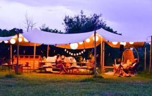 a group of people sitting under a tent at Le Brasseur Logements - Tents in Saint-Caprais