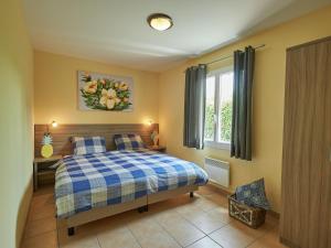 ein Schlafzimmer mit einem Bett mit einer blau-weißen karierten Decke in der Unterkunft Villa with fire place in Loire region in Les Forges