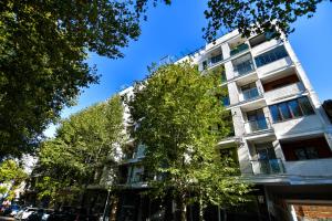 a tall white building with a tree in front of it at Perfect Place in Kutaisi