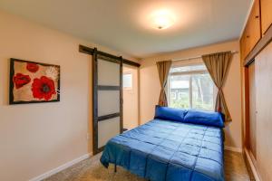 a bedroom with a blue bed and a window at Downtown Anchorage Vacation Rental with Garden Views in Anchorage