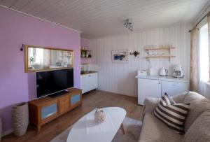 a living room with a couch and a tv and a table at Lilla gröna huset på gården in Härnösand