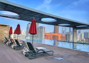 a row of lounge chairs and umbrellas on a roof at Greystone D' Majestic Place in Kuala Lumpur