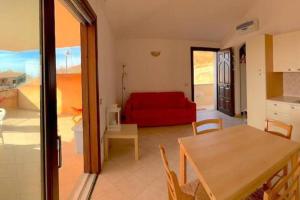 a living room with a red couch and a table at Casa Smeralda - Piscina e vista sul Mare! in Trinità dʼAgultu