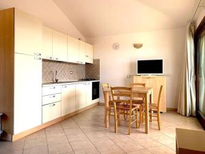 cocina con mesa y sillas y TV en Casa Smeralda - Piscina e vista sul Mare!, en Trinità dʼAgultu