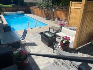 a backyard with a swimming pool with a couch and flowers at Bright poolside walkout two bedroom basement suite in the Okanagan in Penticton