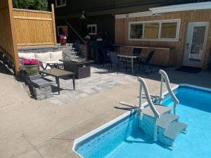 uma piscina com cadeiras, uma mesa e um pátio em Bright poolside walkout two bedroom basement suite in the Okanagan em Penticton
