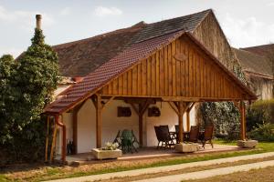 a house with a wooden pavilion with chairs and tables at Penzion Bednářův dvůr in Bohušice