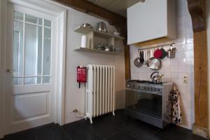 een keuken met een fornuis, een radiator en een deur bij Waterland Achterhuis in Monnickendam