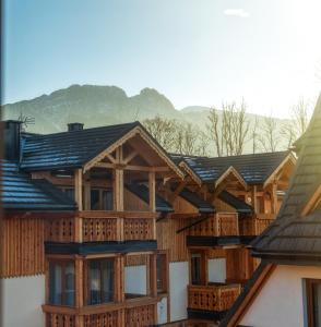 a large wooden house with mountains in the background at Aparthotel Gievont Boutique in Zakopane