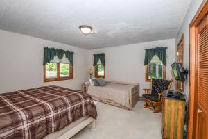 a bedroom with a bed and a tv and a chair at Slip Away Chalet in McHenry
