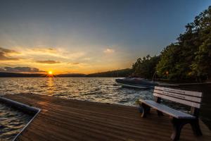 a bench sitting on a dock near the water with a sunset at Sunset View in Swanton