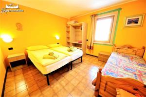 1 dormitorio con paredes amarillas, 1 cama y ventana en Appartamenti Barin, en Livigno
