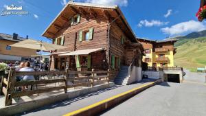 een houten gebouw waar mensen buiten staan bij Appartamenti Barin by Livigno Accomodation in Livigno